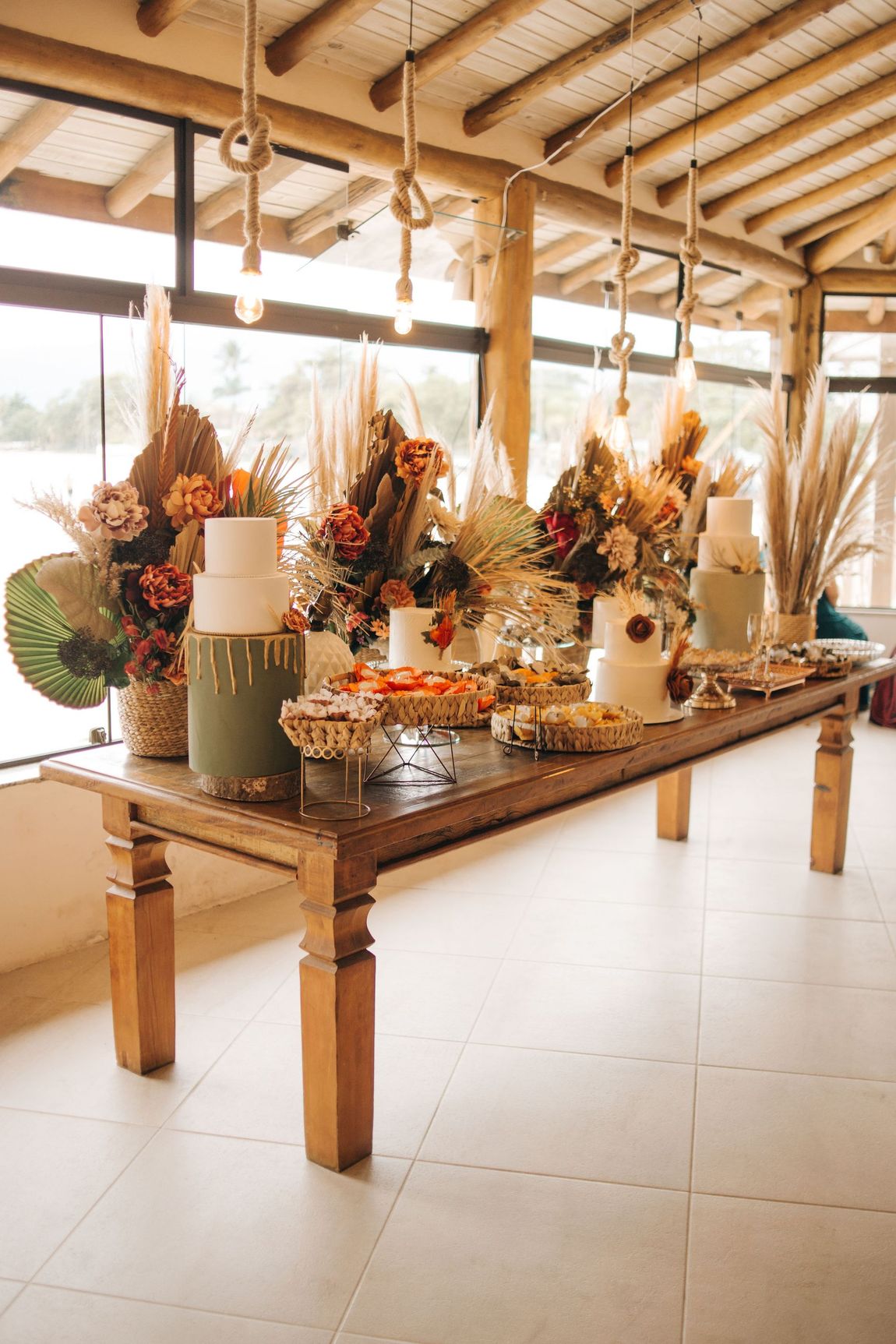 Mesa de bolo com flores, tons rosados e detalhes boho